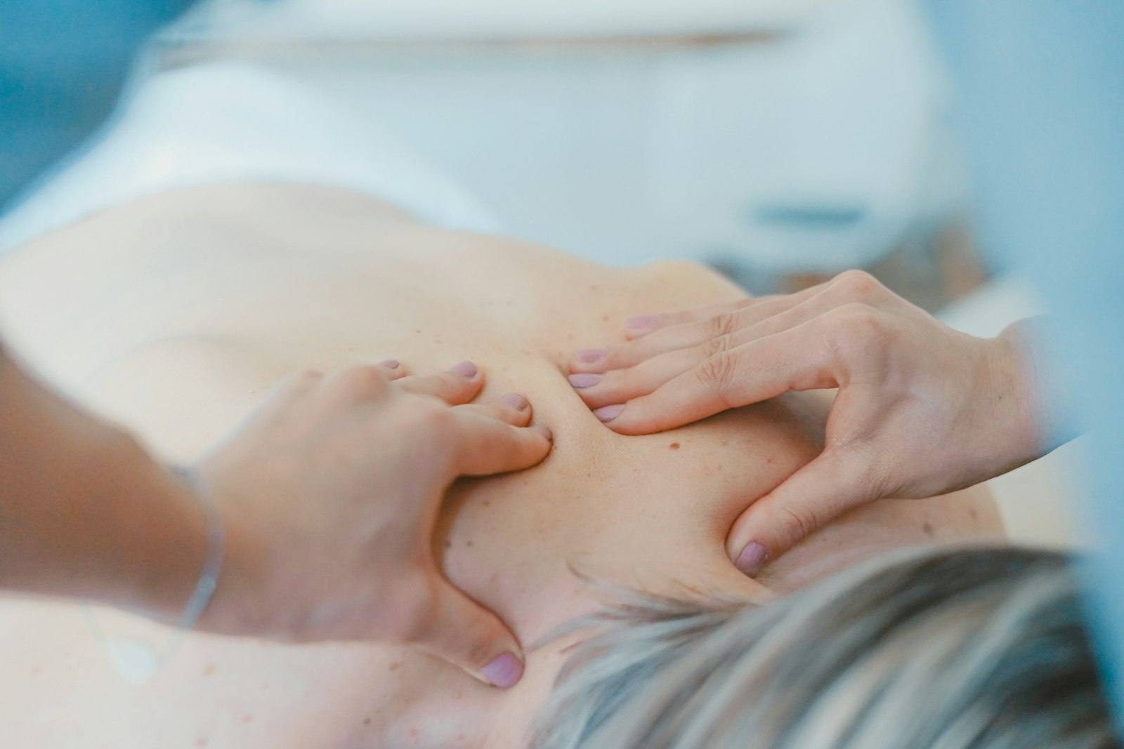 Therapist releasing tension in a client’s neck and shoulder