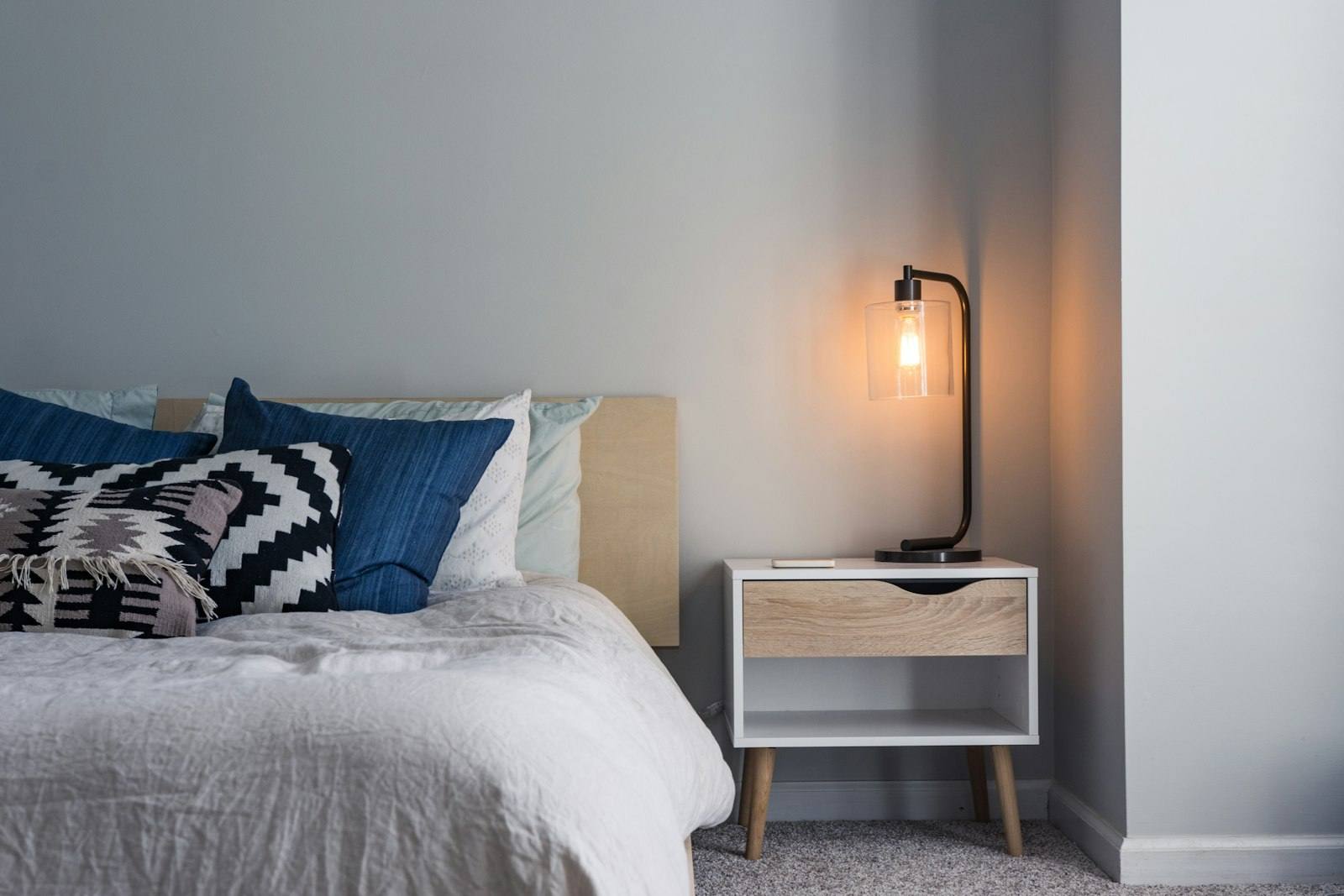A quiet, tidy bedroom at home with a bedside lamp