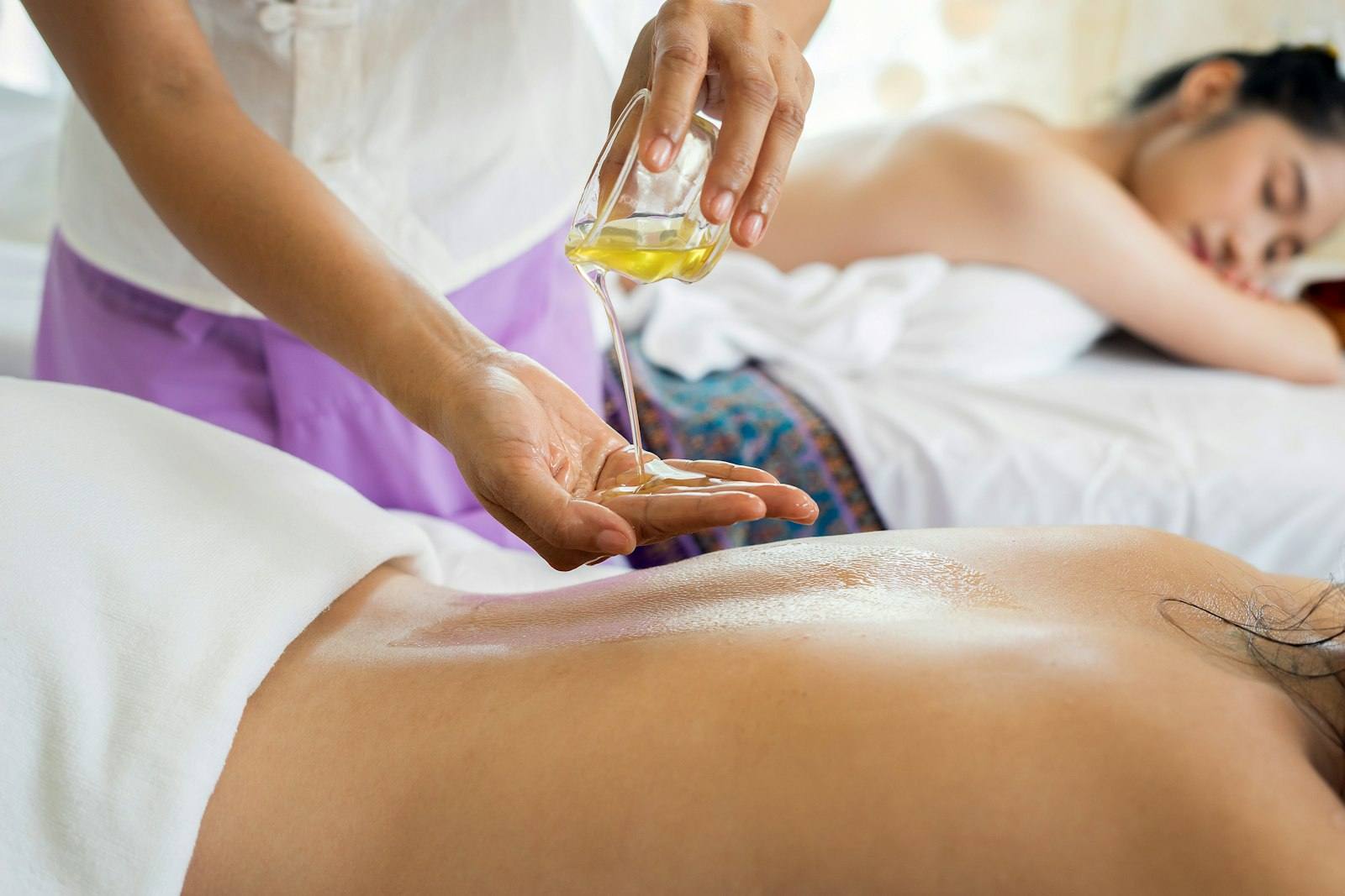 Massage therapist pouring warm oil before a back massage